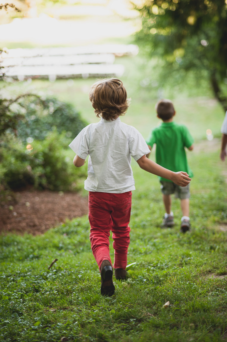 A kid runs down a grassy hill in this lifestyle photo by Leah Verwey.