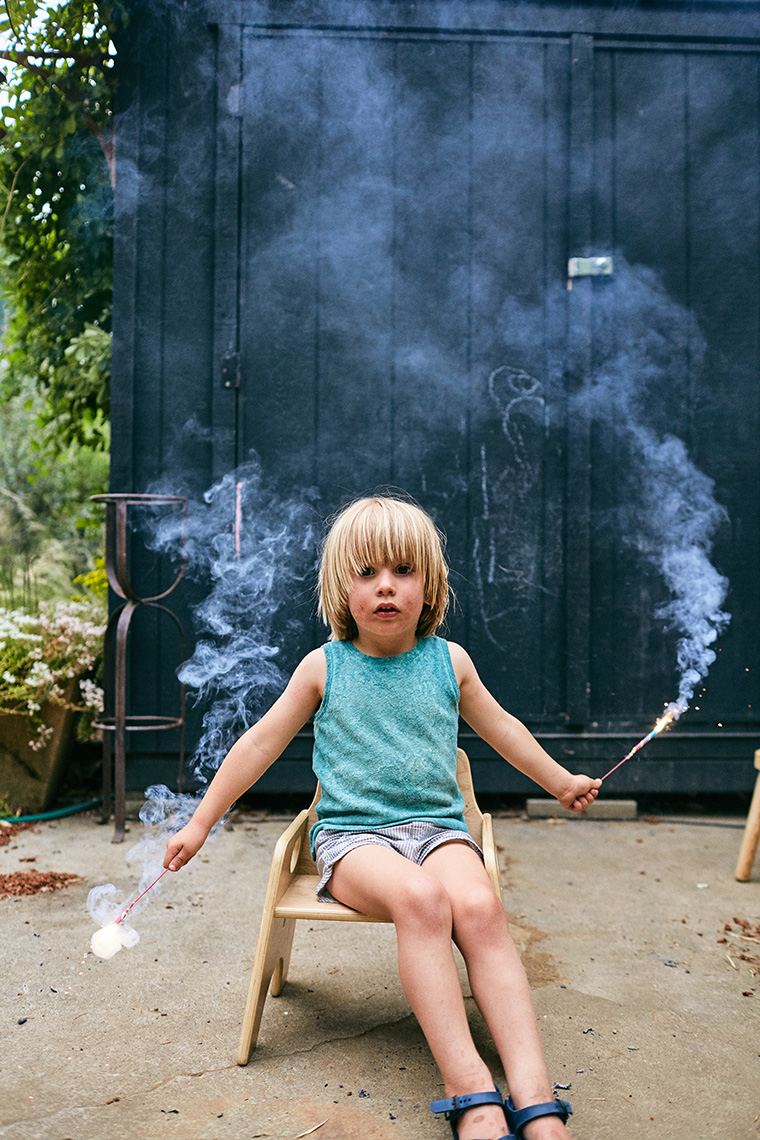 A young kiddo holds sparklers with a mute expression. Image by Leah Verwey
