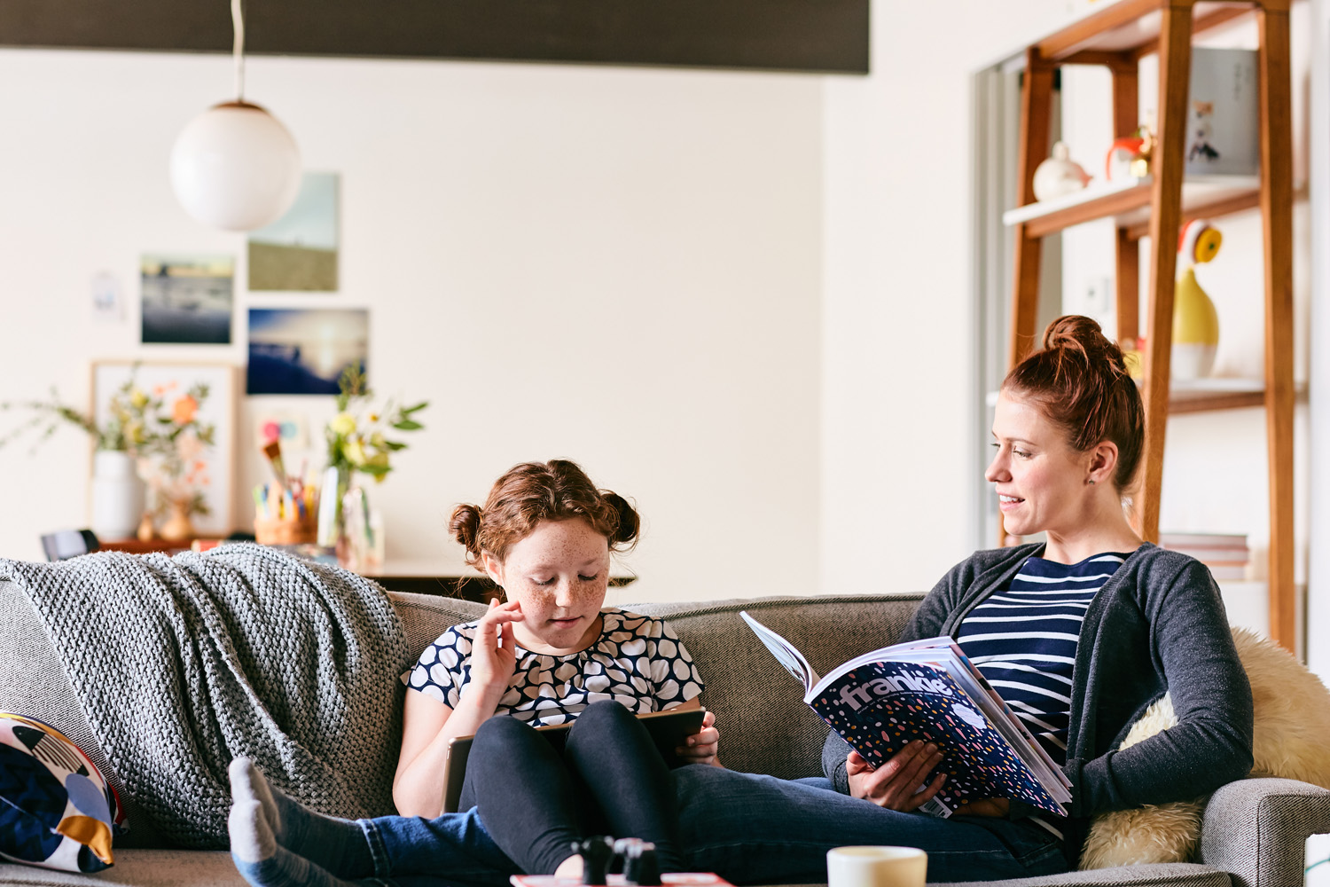 A mom and daughter read books on the couch in this lifestyle image by Leah Verwey