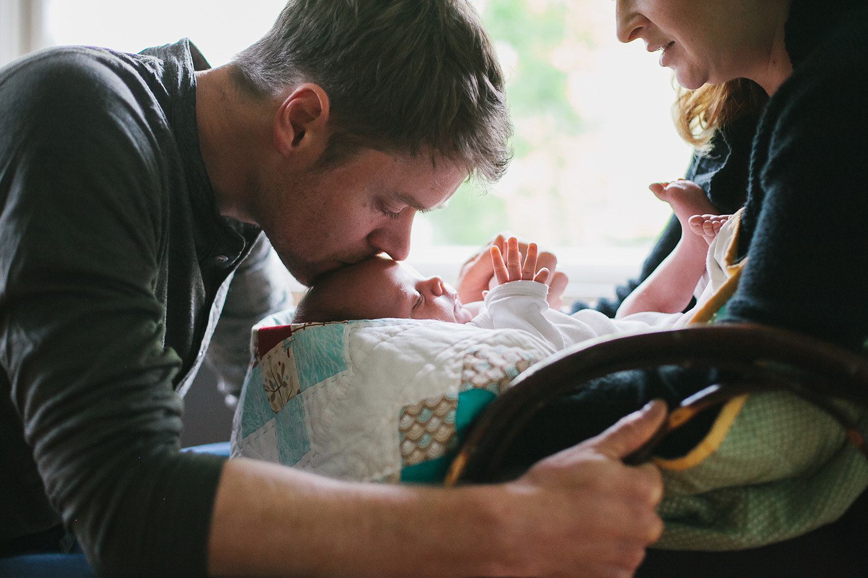 A couple kiss their new baby, by Portland lifestyle photographer Leah Verwey