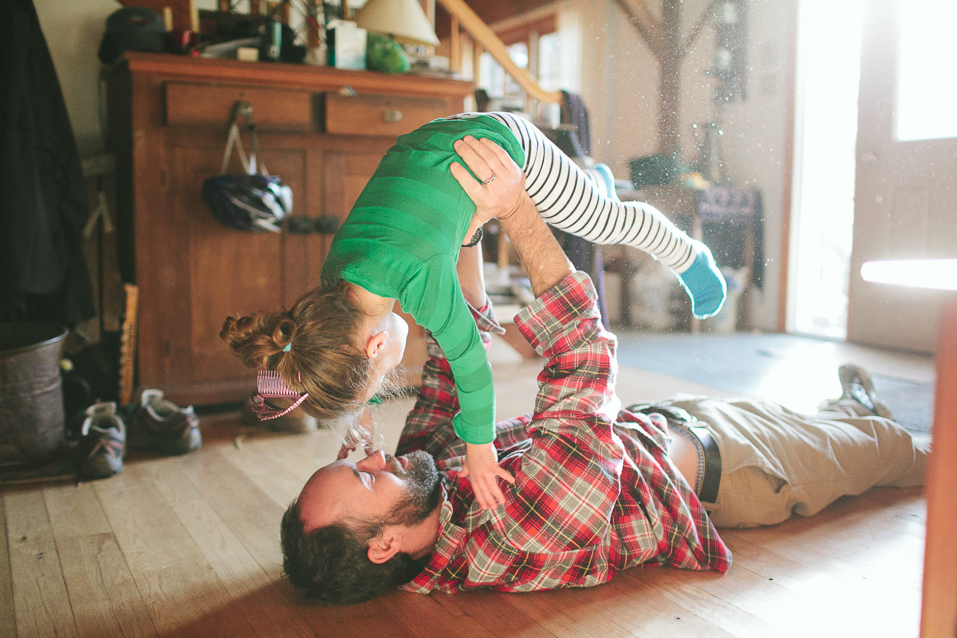 A dad plays airplane with his kid in a lifestyle photo