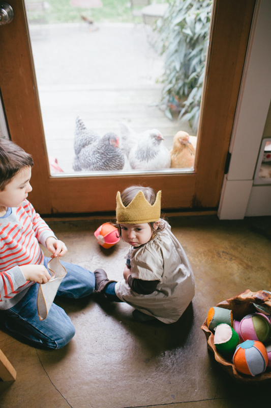 Two young kids look at back yard chickens in Portland, Oregon.